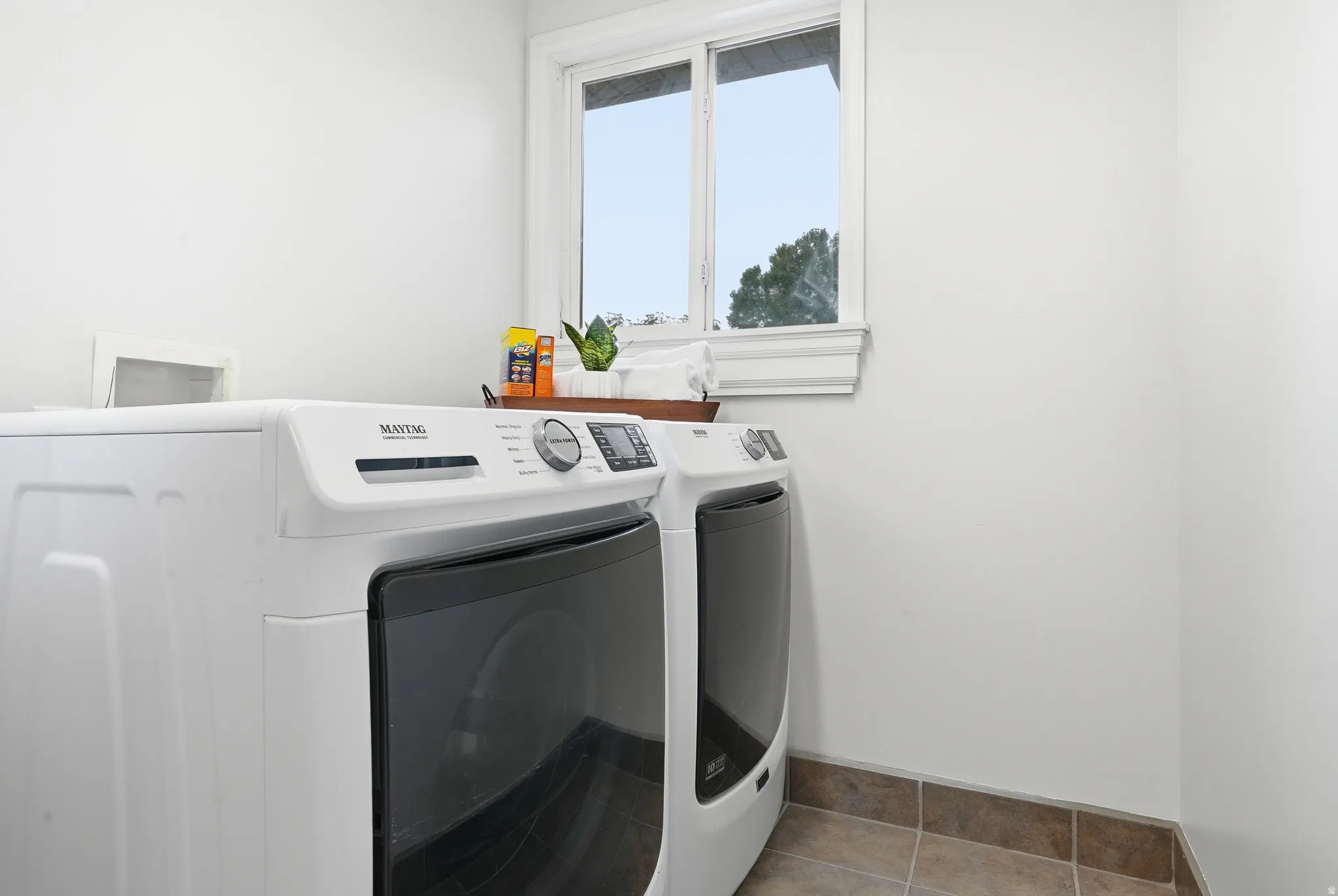 White appliances featuring a front-load washer and dryer, tile flooring, and a single window