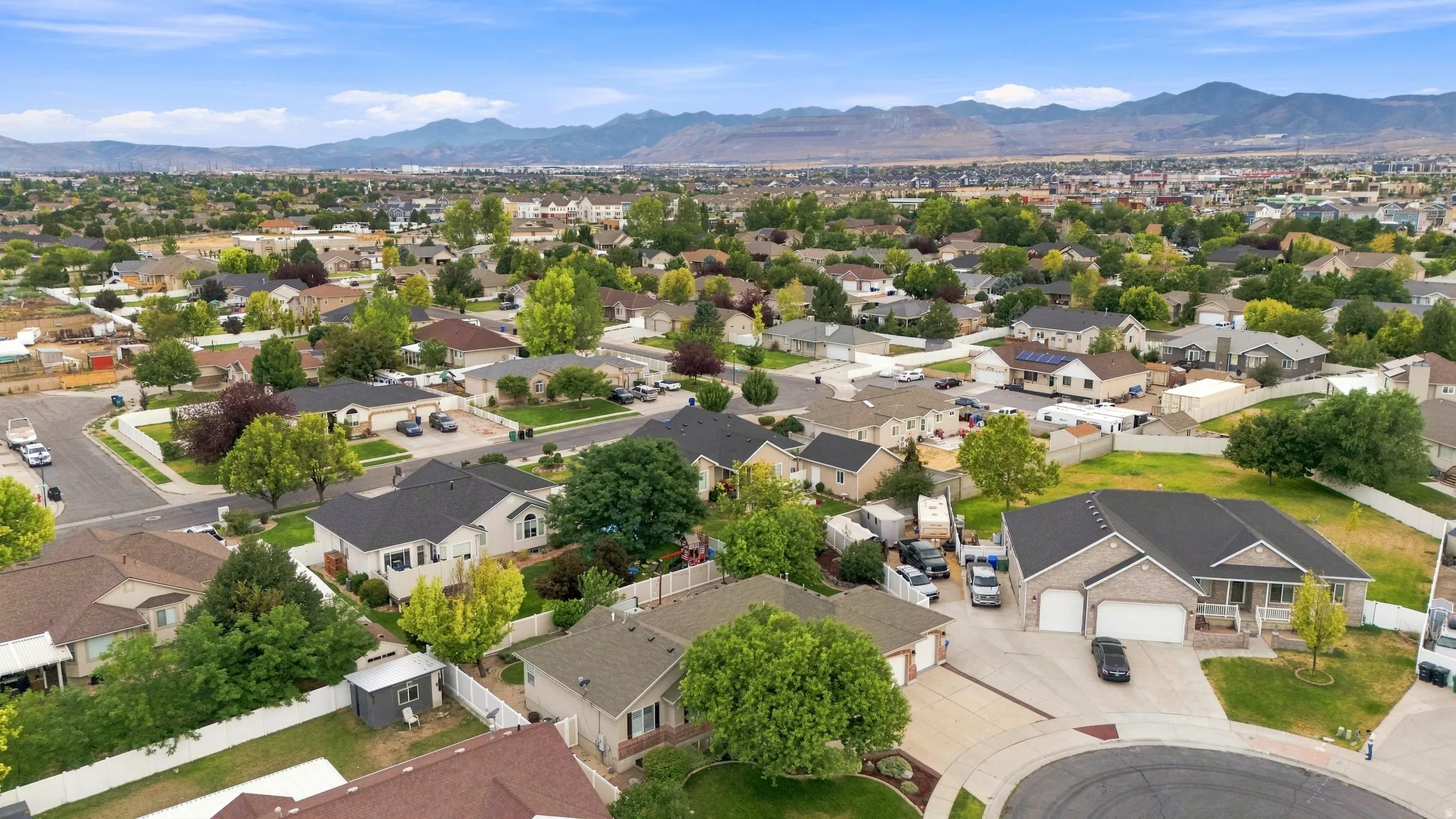 Aerial perspective showcasing this residential community nestled against mountain backdrop, featuring single-family homes with varied architectural styles, mature landscaping throughout the neighborhood, and expansive lot sizes with manicured lawns and es