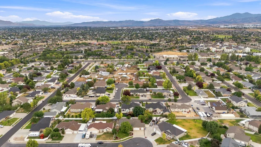Residential neighborhood with mature trees, paved streets, and distant mountains