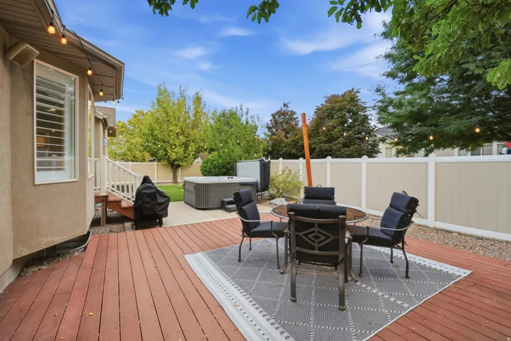 Spacious wood deck with an integrated hot tub and stone patio area