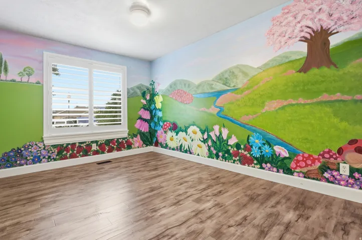 Wood-finish flooring, vibrant mural wall art, white window trim, and louvered window shutters