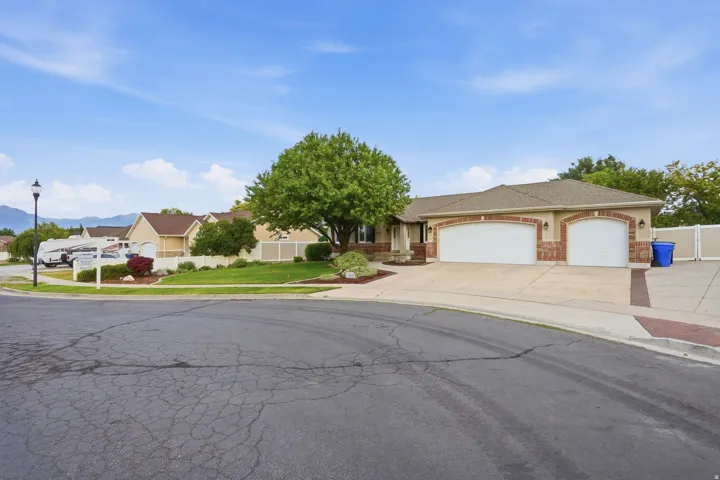Well-maintained front lawn, mature shade tree, two-car garage, brick façade accents, and concrete driveway