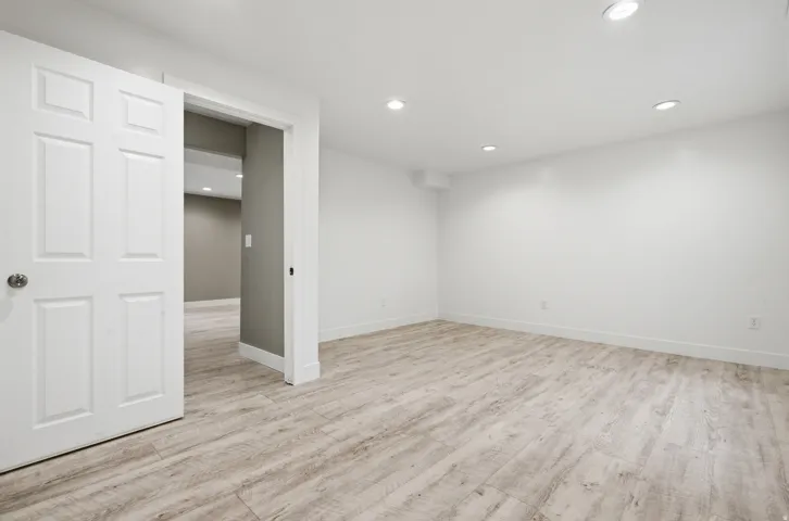 Recessed lighting illuminating the white walls and wood-finish flooring