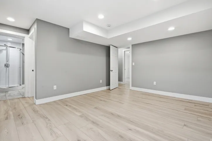 Recessed lighting, wood-finish flooring, and a neutral wall color