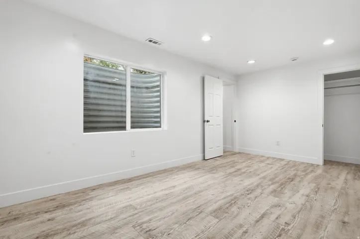 Recessed lighting, wood-finish flooring, white paneled door, and a built-in closet