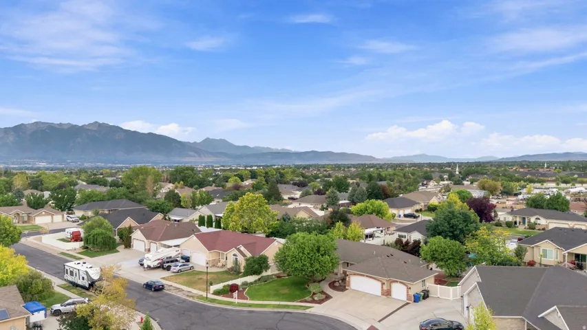Aerial view showcasing a well-established residential neighborhood with mature landscaping, tree-lined streets, and mountain backdrop