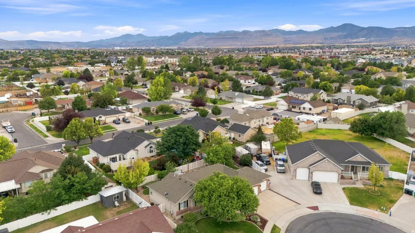 Aerial perspective showcasing this residential community nestled against mountain backdrop, featuring single-family homes with varied architectural styles, mature landscaping throughout the neighborhood, and expansive lot sizes with manicured lawns and es
