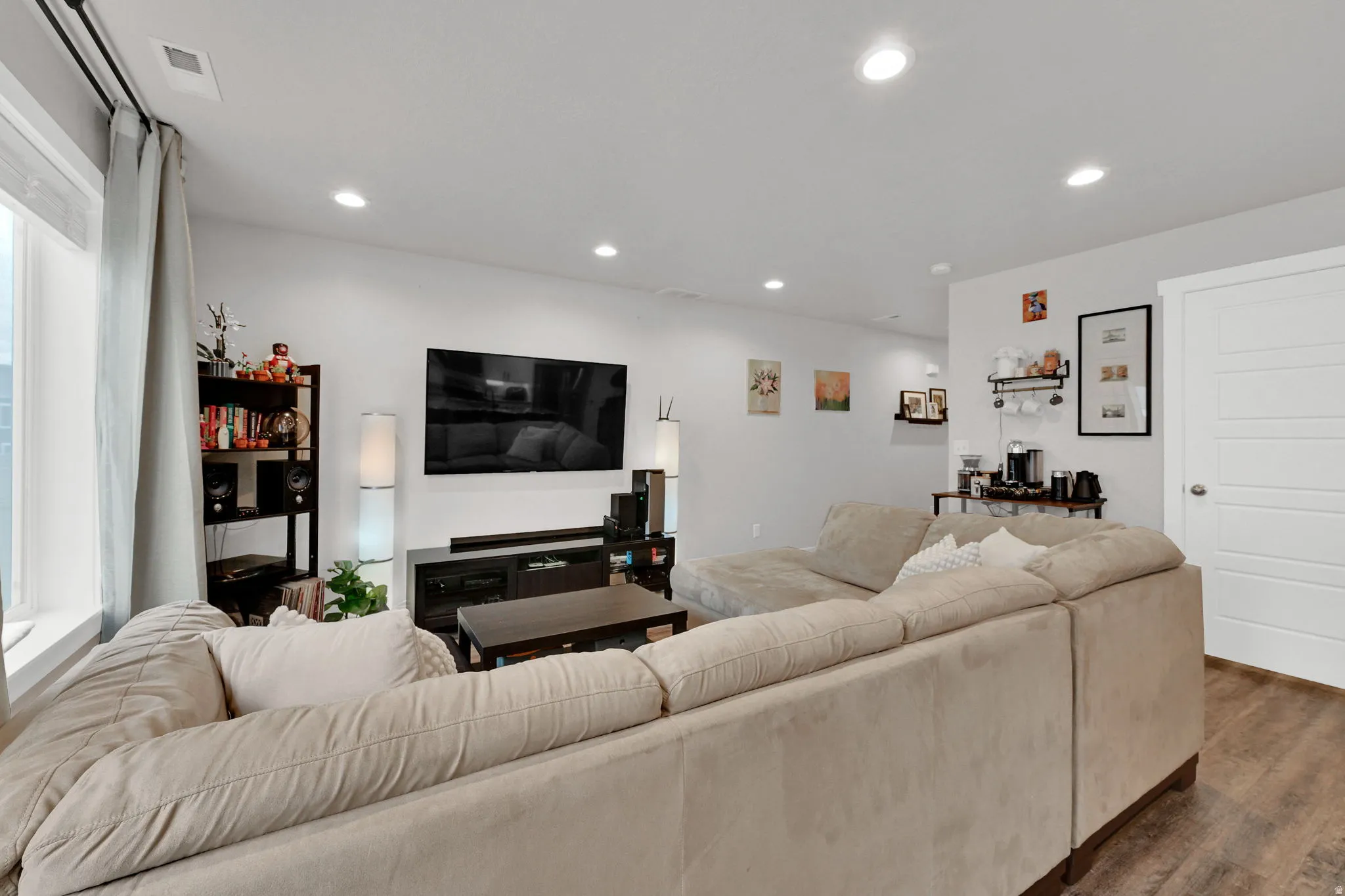 Recessed ceiling lighting, LVP wood-finish flooring, white trim, and a paneled door