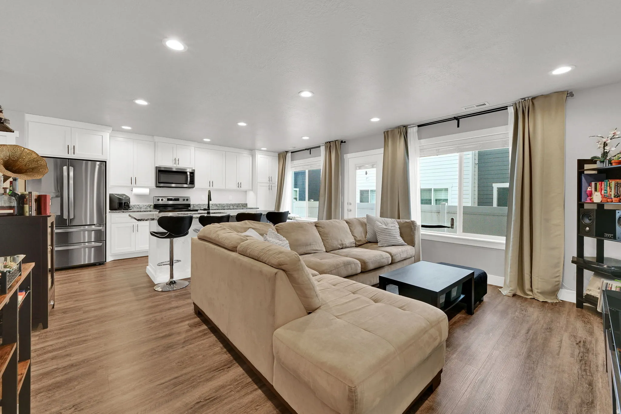 Open-concept living area featuring a sectional layout with  LVP wood-finish flooring throughout