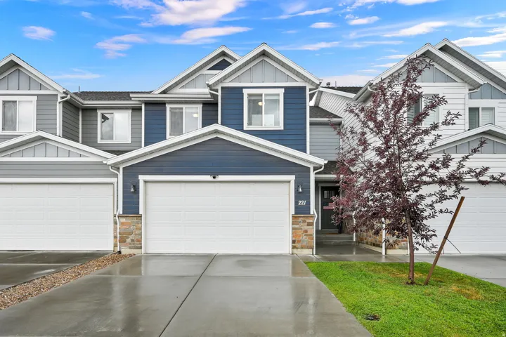 Multilevel townhouse with a two-car garage, stone and siding exterior, and individual entry