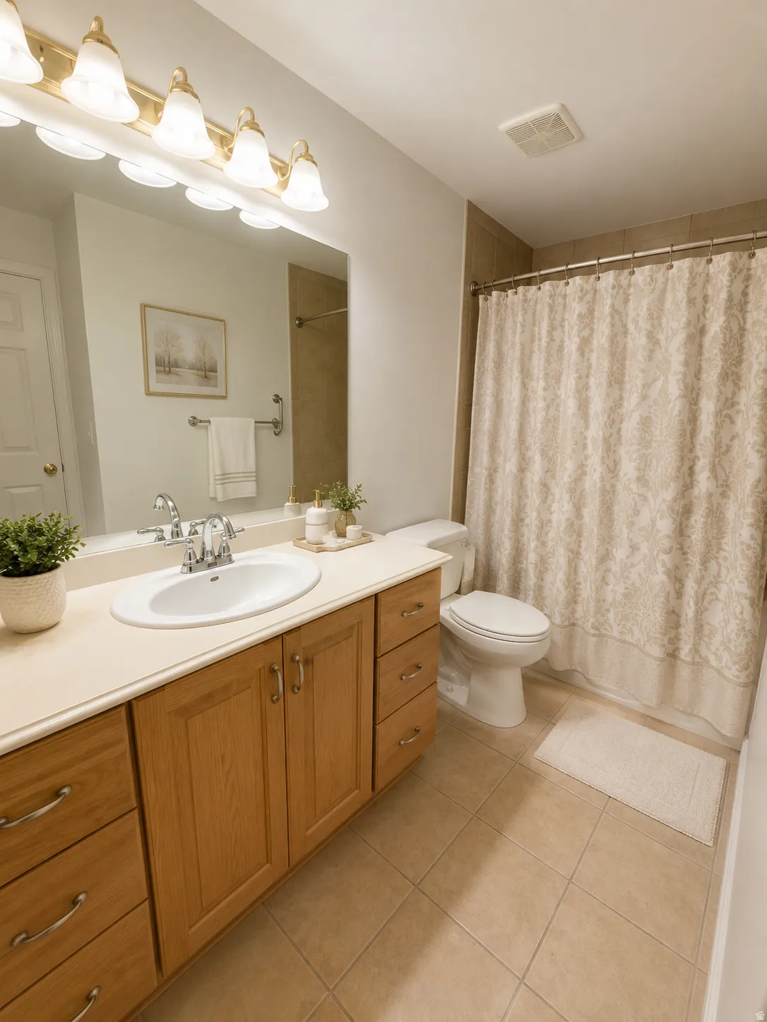 Full-width vanity with wood-finish cabinetry, integrated sink, and an expansive mirror