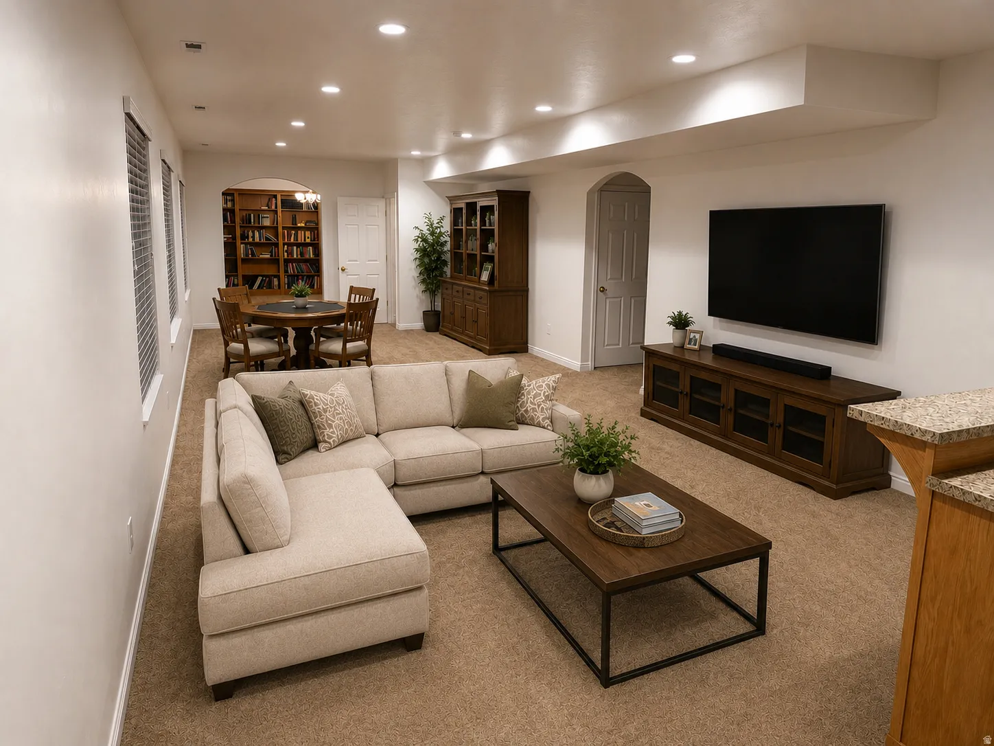 Recessed lighting throughout, arched doorways, a built-in bookshelf, and a carpeted floor