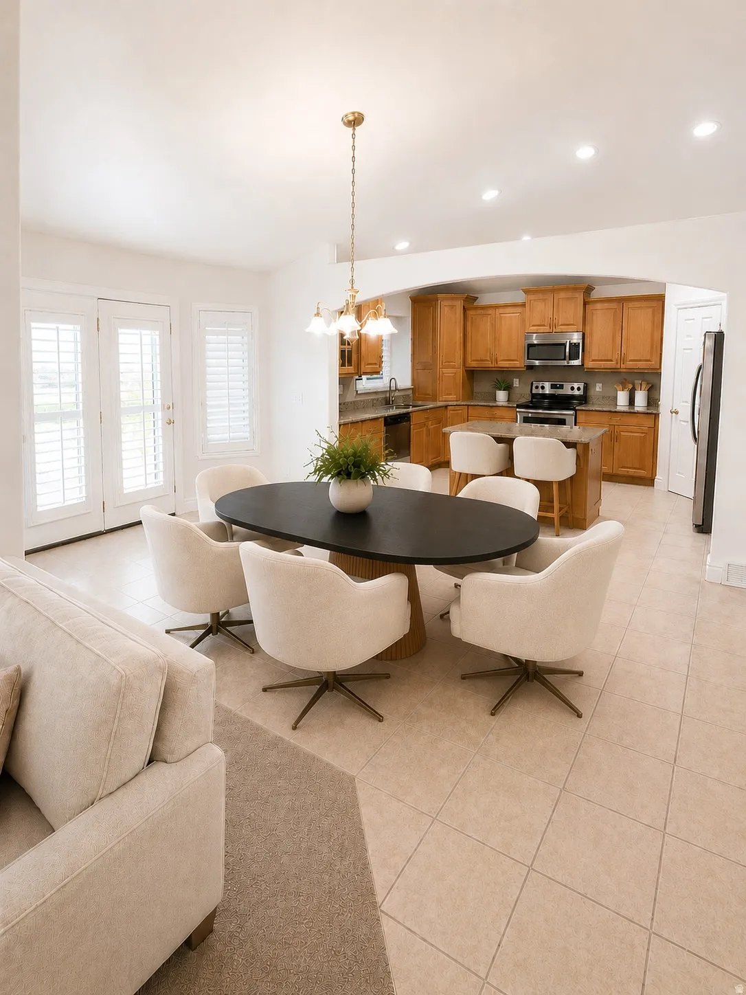 Recessed lighting, tile flooring, French doors with plantation shutters, an arched doorway, and wood cabinetry in the kitchen
