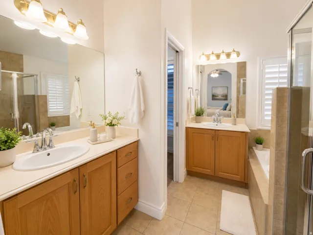 Dual vanities with integrated sinks, wood-finish cabinetry, and neutral countertops