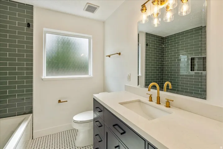 bathroom featuring  soft-close cabinetry, quartz countertop, and brass fixtures