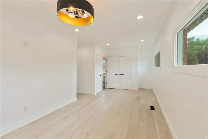 Recessed lighting, wood-finish flooring, and white walls throughout
