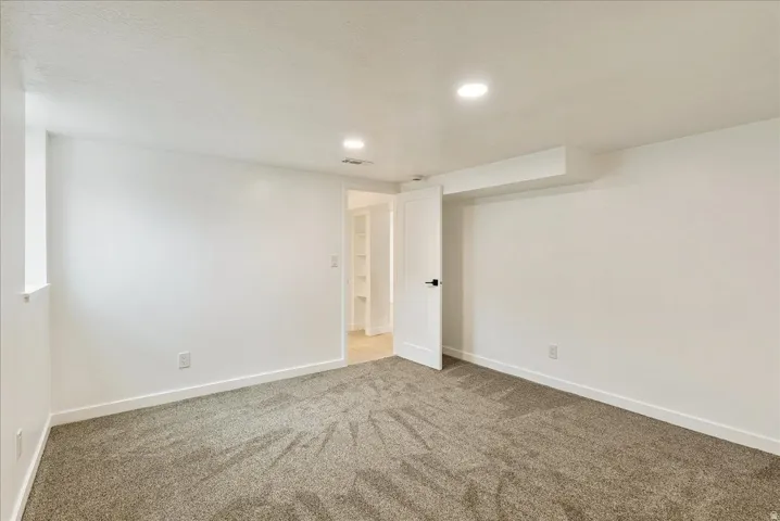 Spacious carpeted bedroom with neutral wall finishes, recessed ceiling lighting