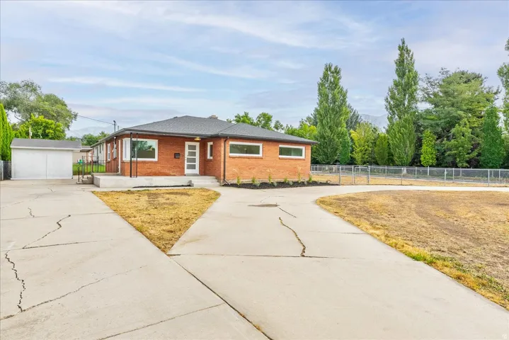 Charming brick ranch home with modern updates, featuring a clean geometric driveway layout and expansive front grounds