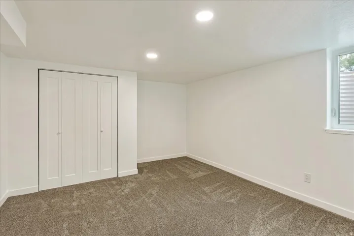 Spacious bedroom with neutral wall finishes, recessed ceiling lighting, and a large closet with white bifold doors