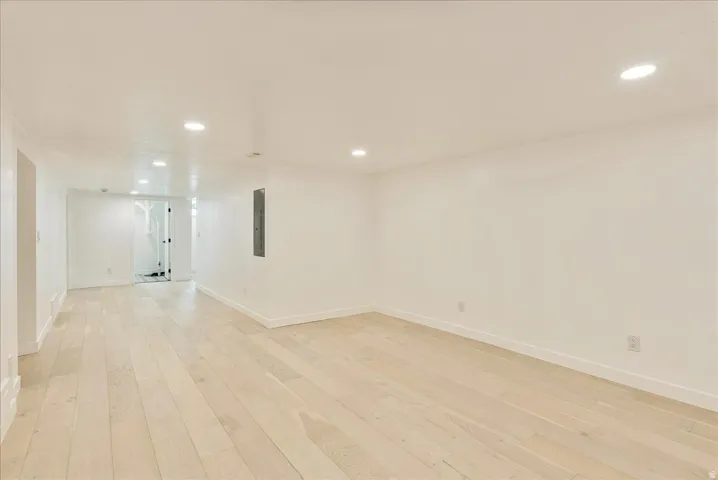 Bright, open recreational space featuring light wood-finish flooring throughout, recessed ceiling lighting, and clean white walls