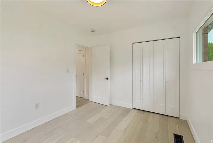 Light wood-finish flooring, white walls, and a window with natural light