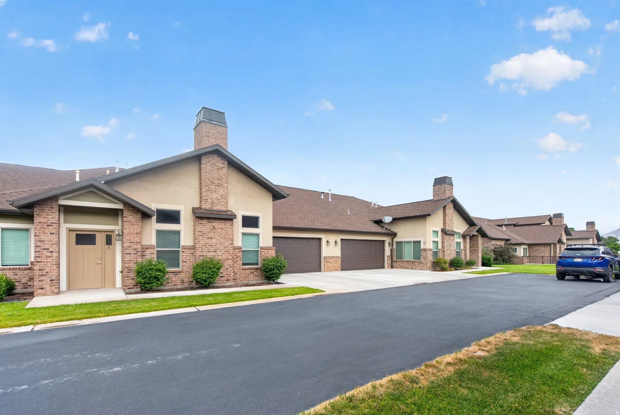 Brick and stucco exterior with multiple gabled roofs, an attached garage, and a paved driveway