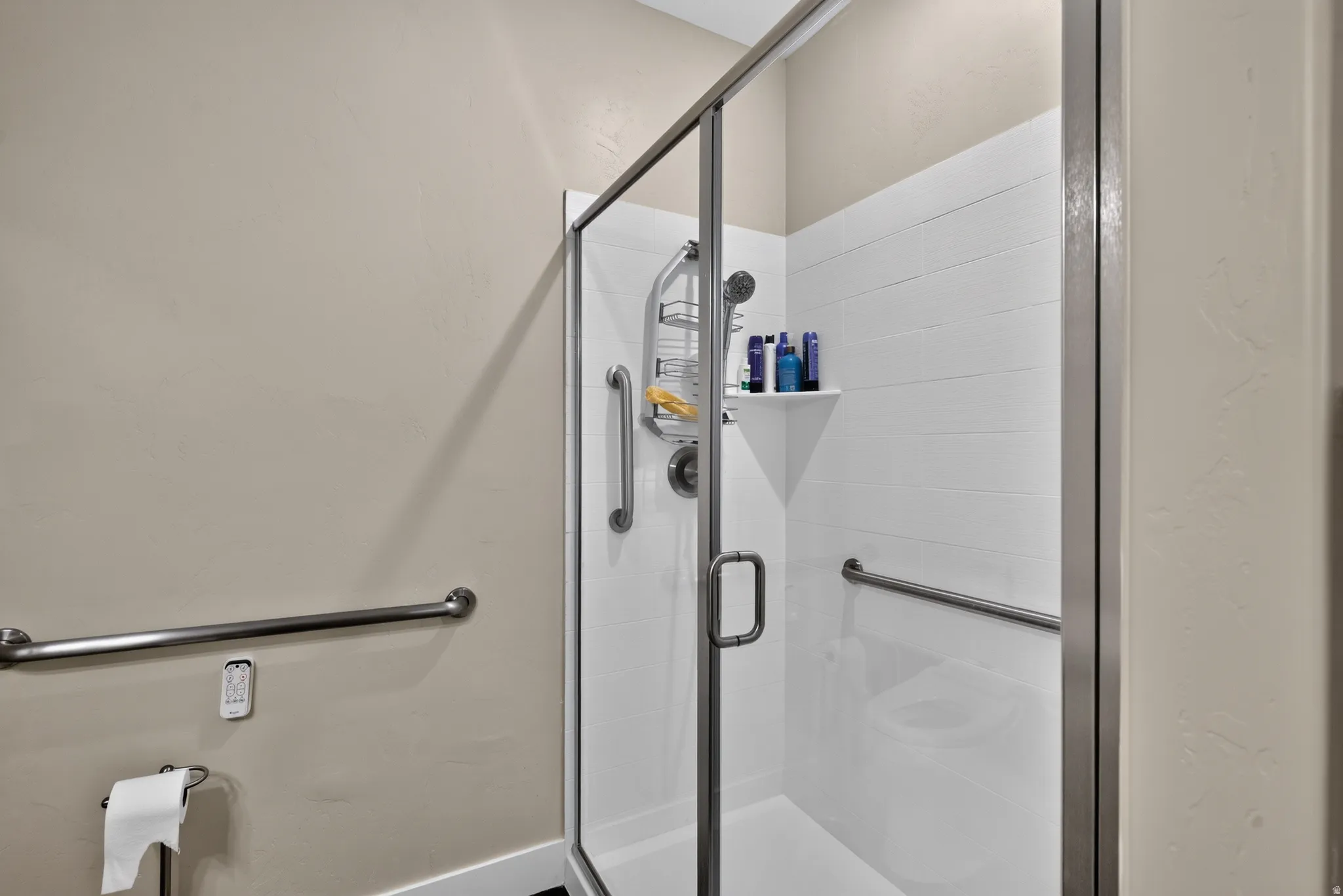 Primary bathroom shower with frameless glass shower enclosure with chrome hardware