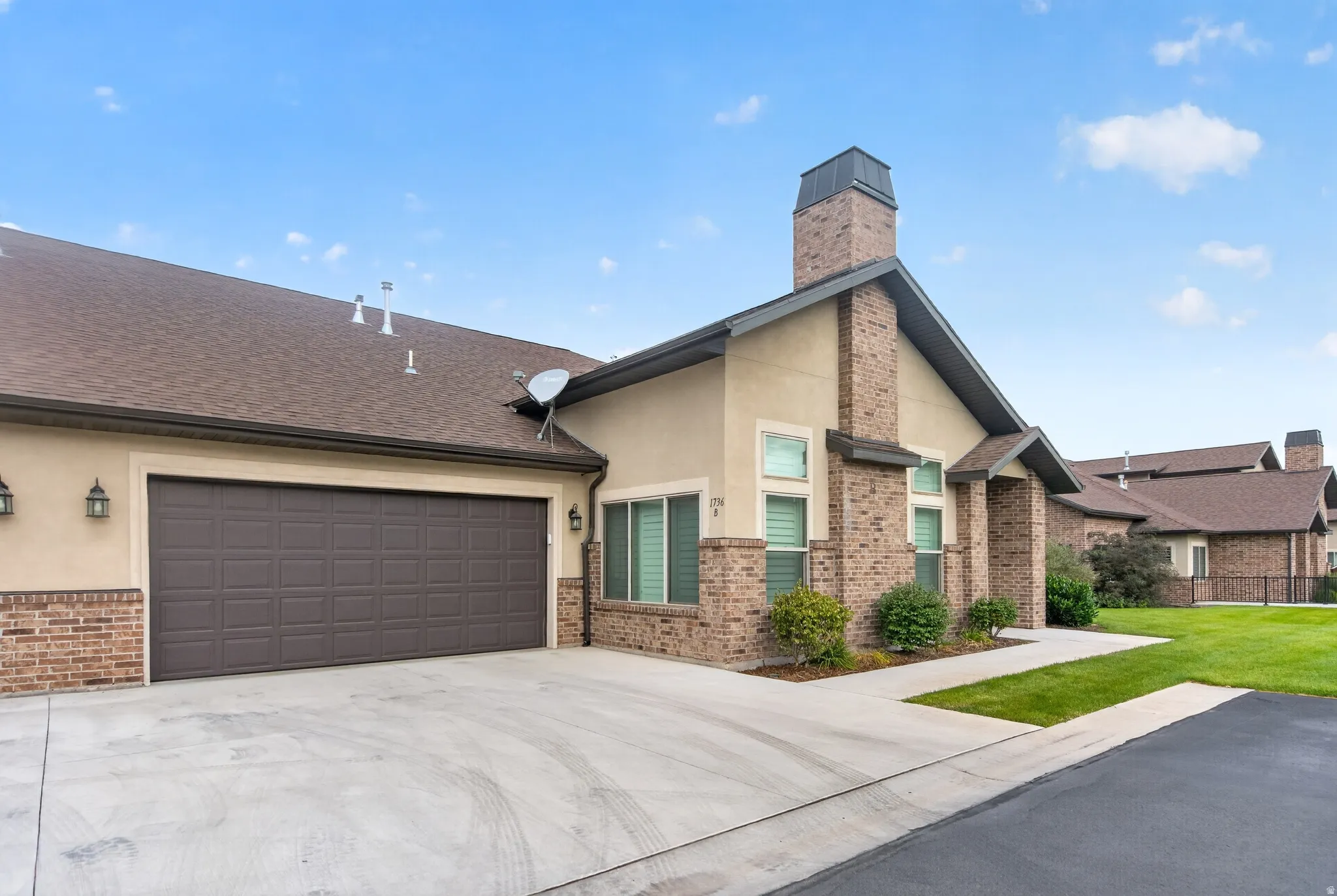 Welcoming brick and stone exterior with a two-car attached garage featuring a dark finish door