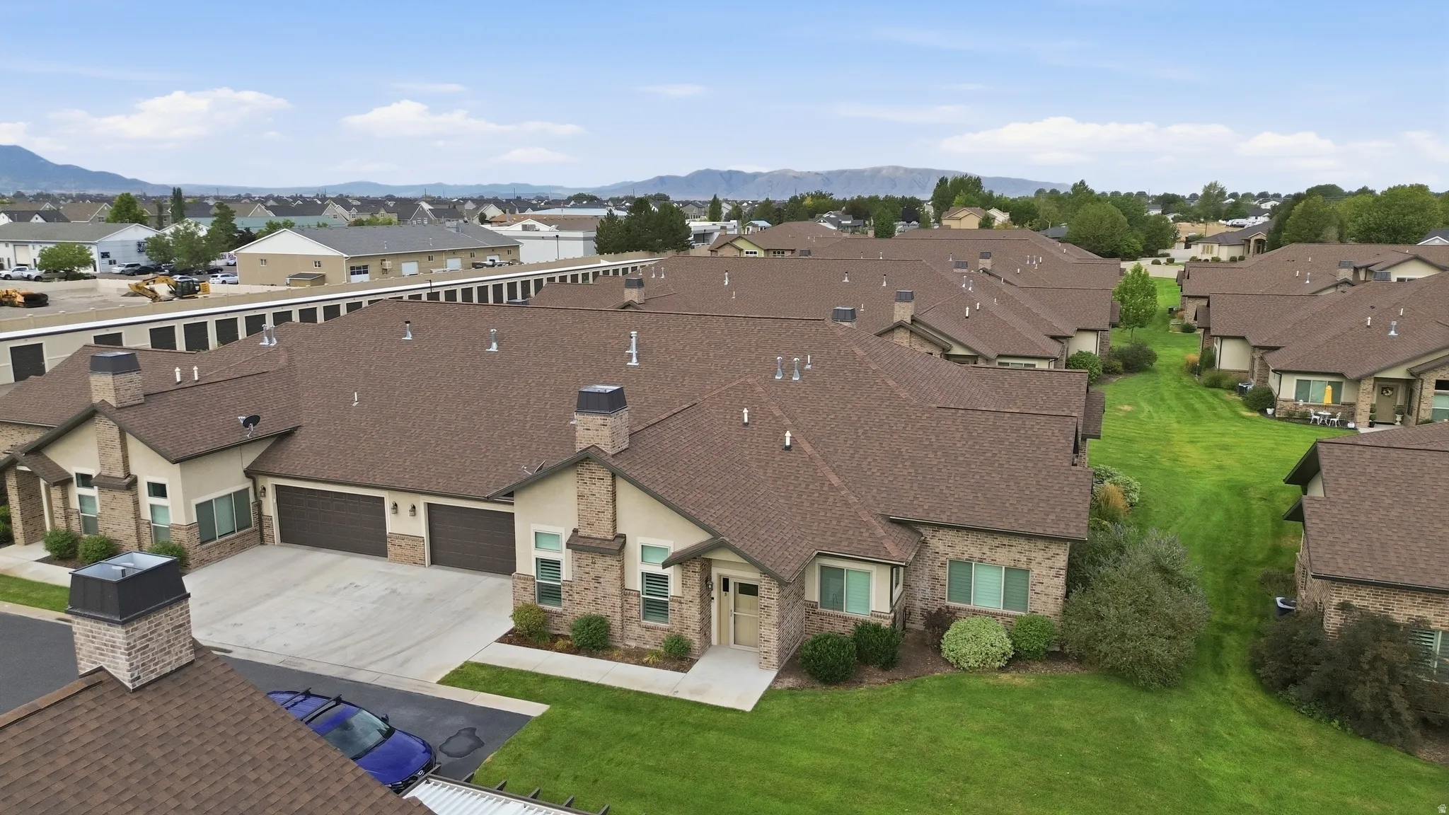 Expansive residential community featuring multiple single-family homes with architectural consistency, brown asphalt shingle roofing, and manicured landscaping throughout