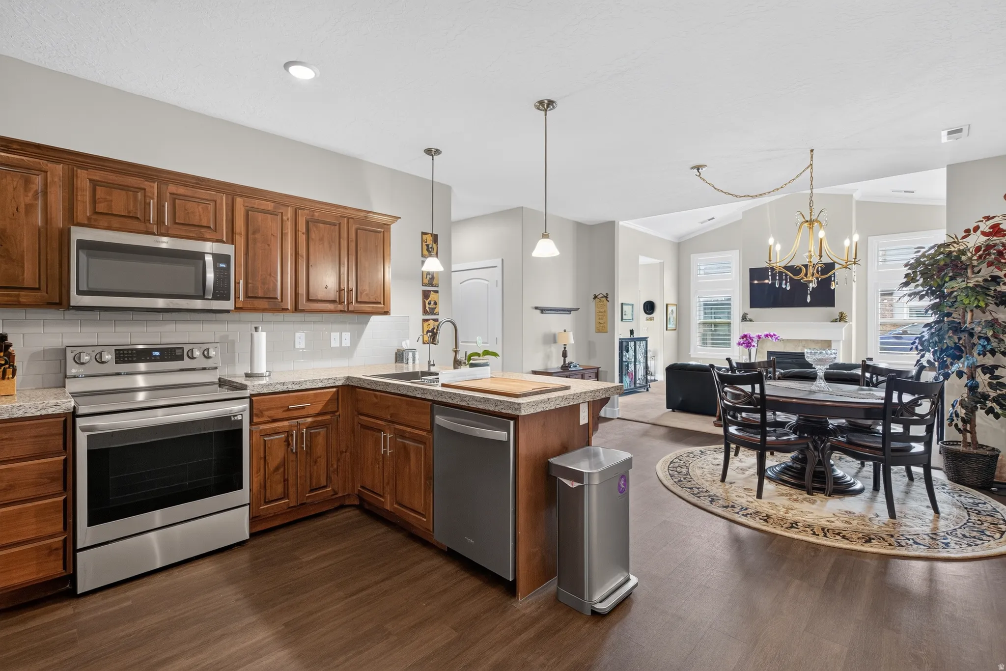 Kitchen featuring wood-finish flooring, stainless steel appliances, wood cabinetry, and a granite-style countertop
