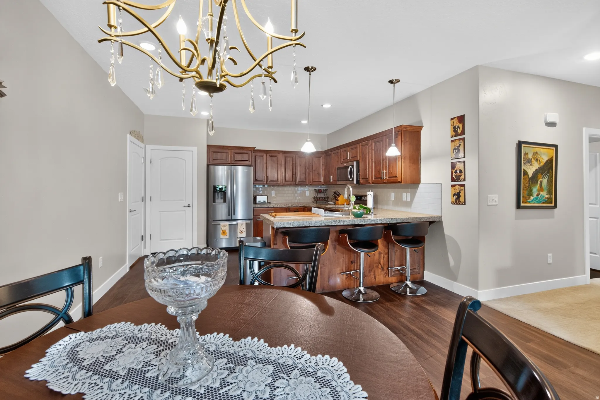 Open-concept kitchen with wood-finish flooring, stainless steel appliances, and a breakfast bar