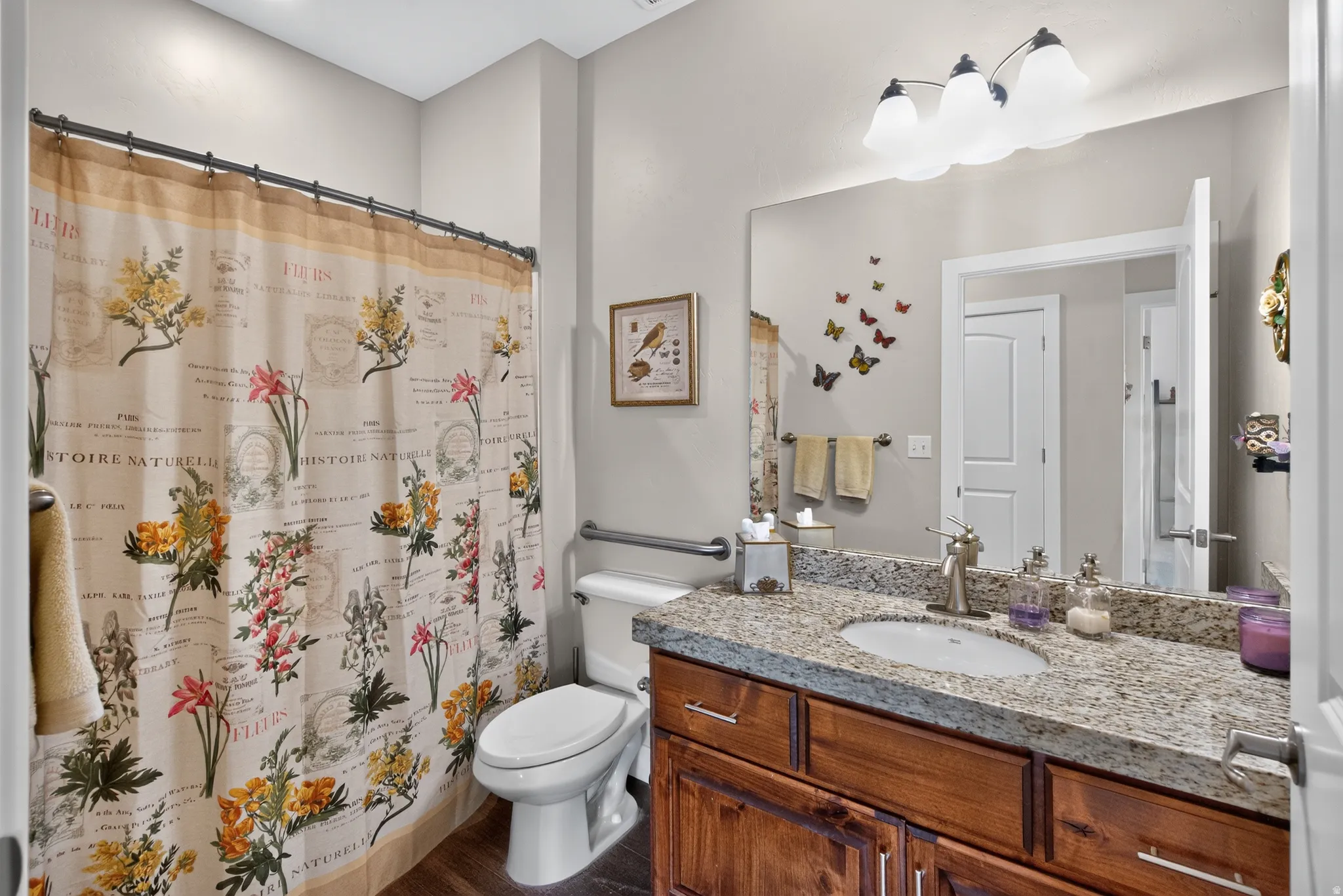 Spa-inspired bathroom featuring a wood-finish vanity with dual sinks, granite countertops, and polished chrome fixtures