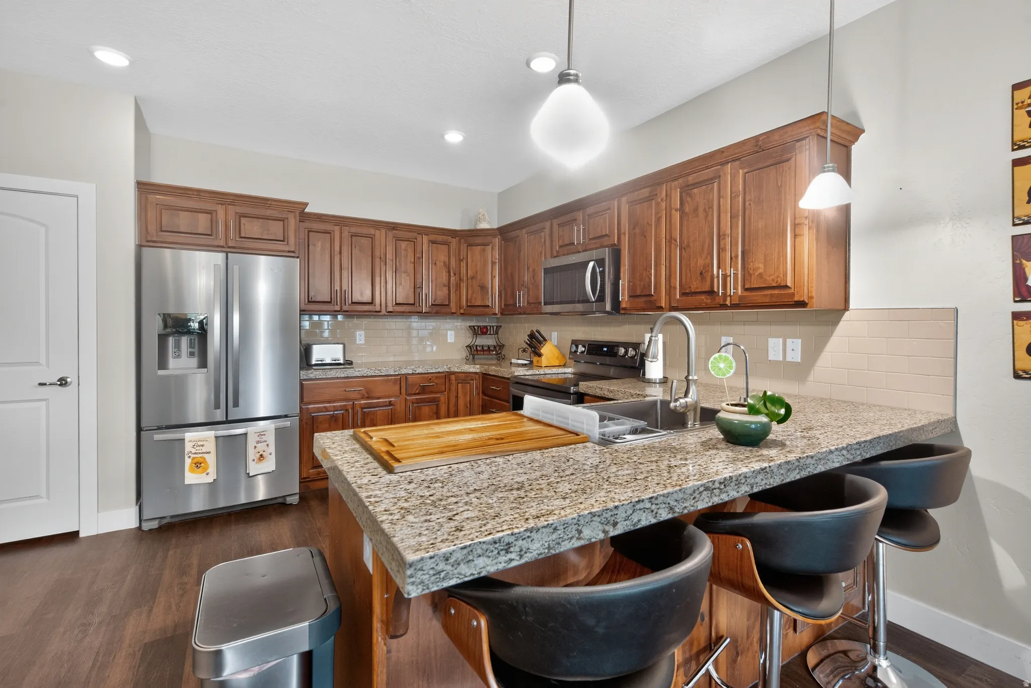 Chef's kitchen featuring rich wood cabinetry, stainless steel appliances including a professional-grade gas cooktop, and a spacious granite-topped island with seating for multiple guests