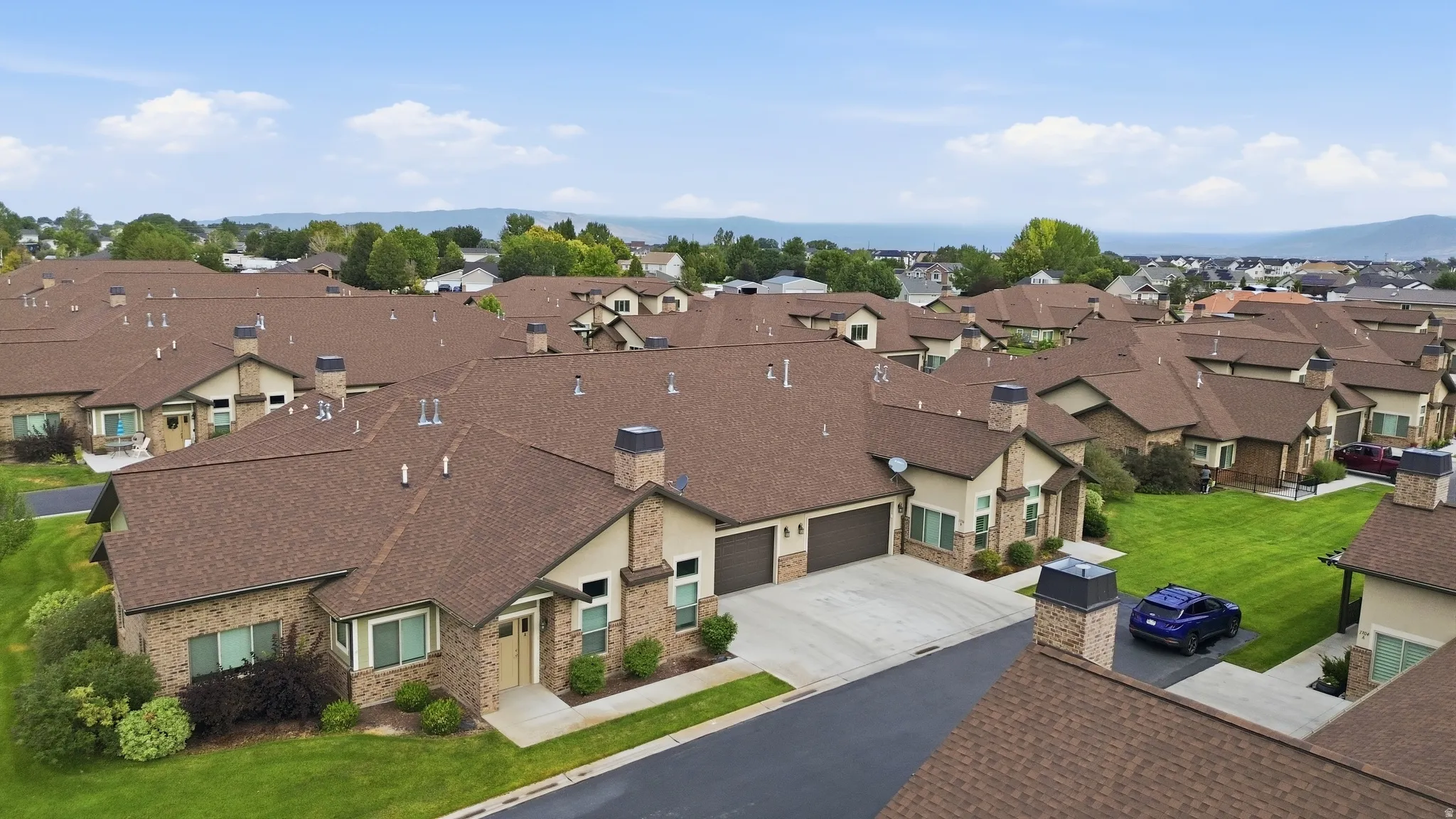 Stunning residential property showcasing a brick and stone exterior with a professionally paved driveway, attached garage, and manicured lawn