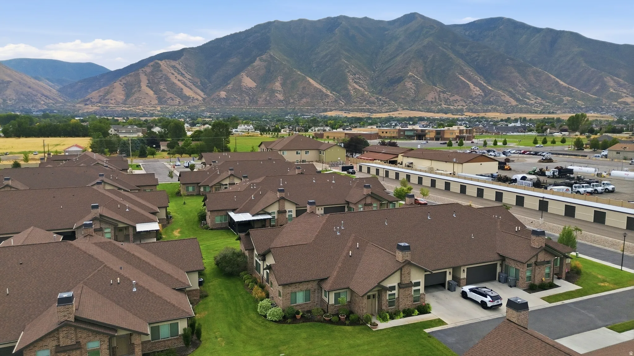 Sprawling residential community featuring multiple brick-constructed homes with dark-toned roofing, manicured lawns, and paved driveways