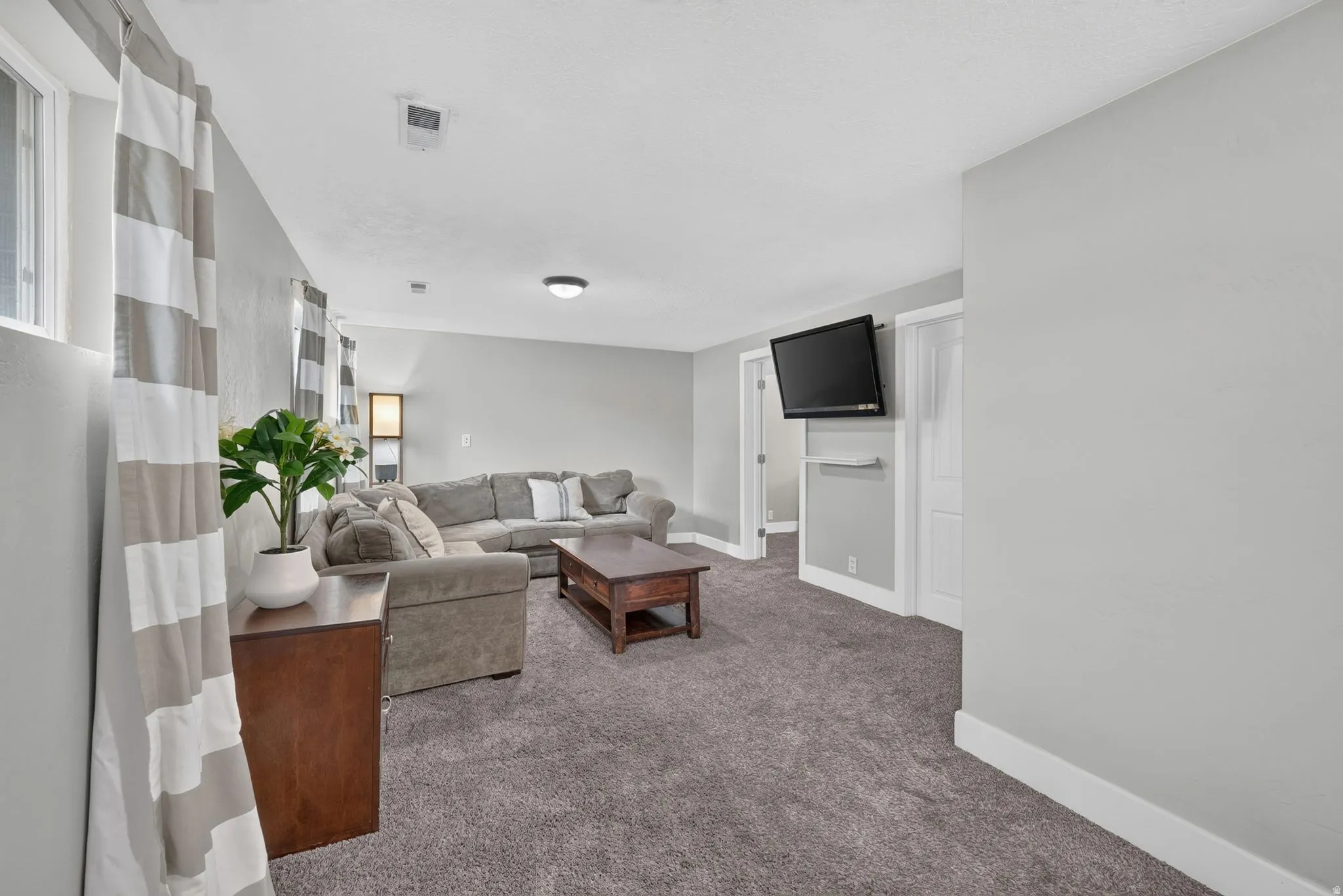 Spacious finished basement with plush carpeting, recessed ceiling lighting, and abundant natural light from multiple windows