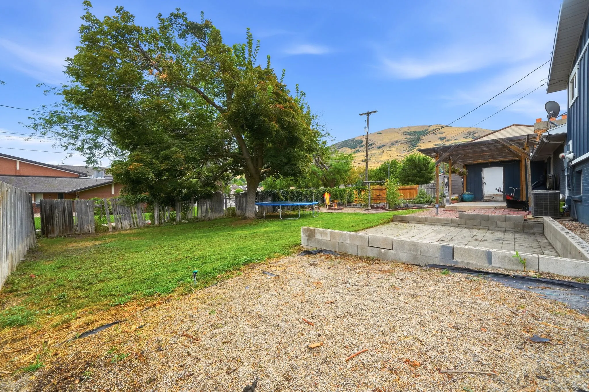 Spacious backyard with mature shade trees and established lawn, concrete patio foundation, and direct access to the residence
