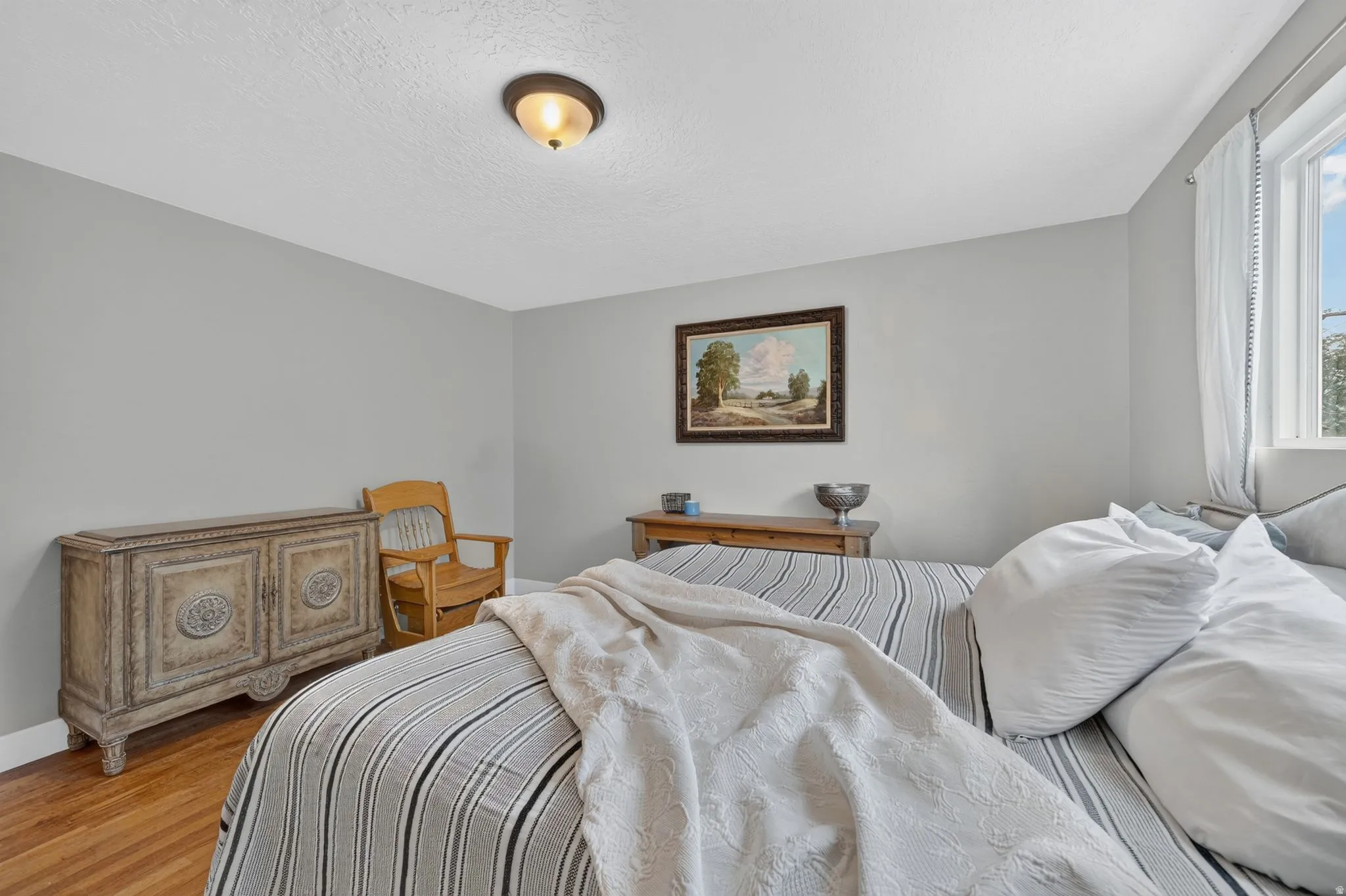 Bright secondary bedroom featuring hardwood flooring, generous natural light from dual windows, and traditional wood-finish cabinetry