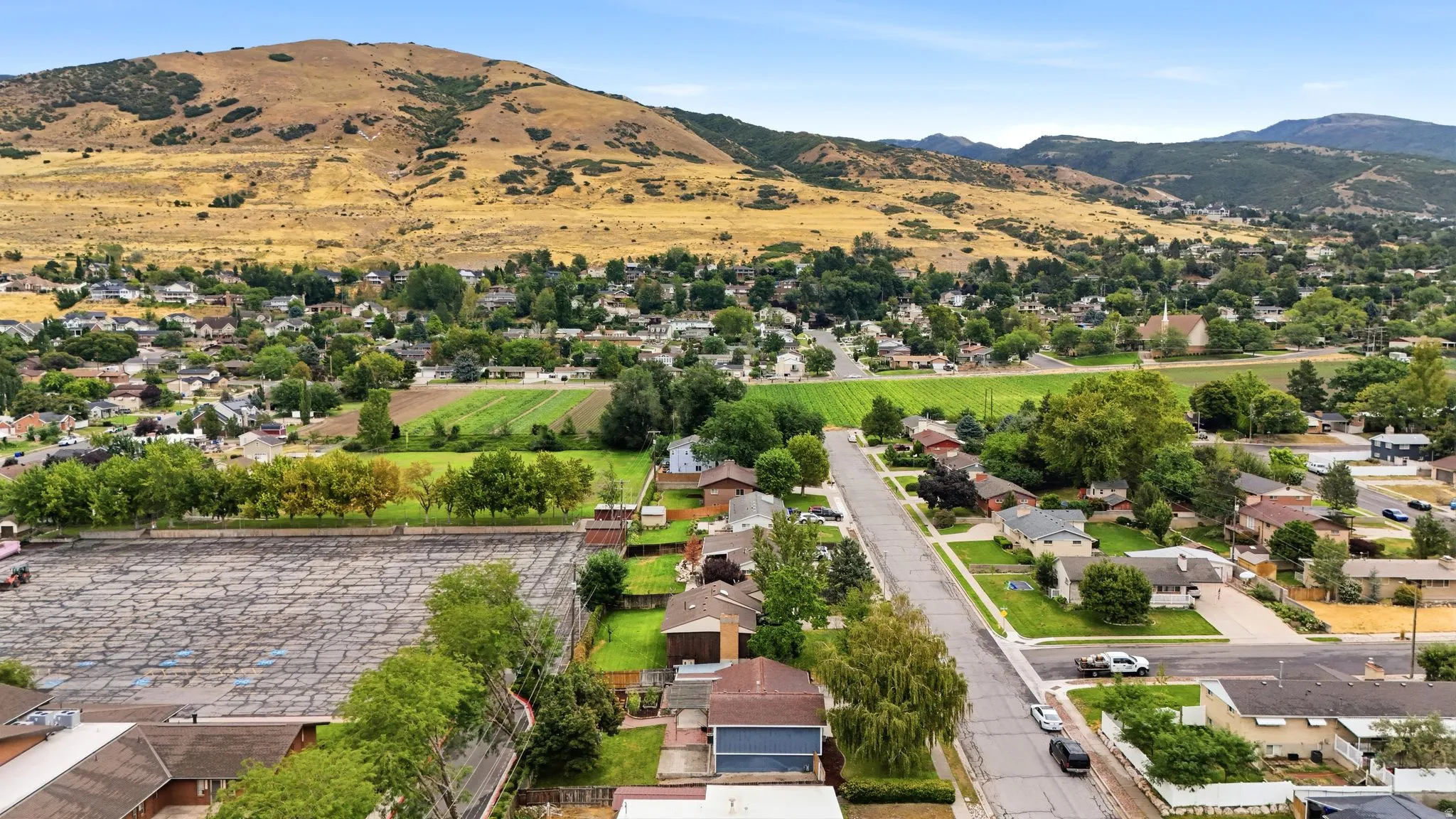Aerial perspective of this residential property showcasing a modern home with a dark-tiled roof, manicured lawn, and mature landscaping