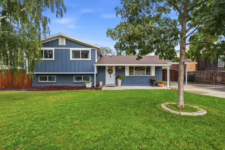 Contemporary split-level home featuring a freshly updated exterior with modern board-and-batten siding in deep blue-gray tones, complemented by clean white trim and a covered front entrance