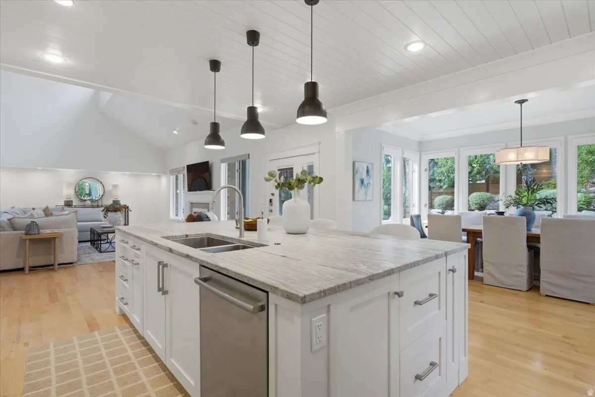 Kitchen island featuring a stainless steel dishwasher, undermount sink, and stone-finish countertop