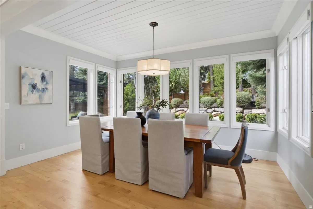 Wood-finish flooring, white shiplap ceiling, multiple large windows, and a chandelier with a drum shade