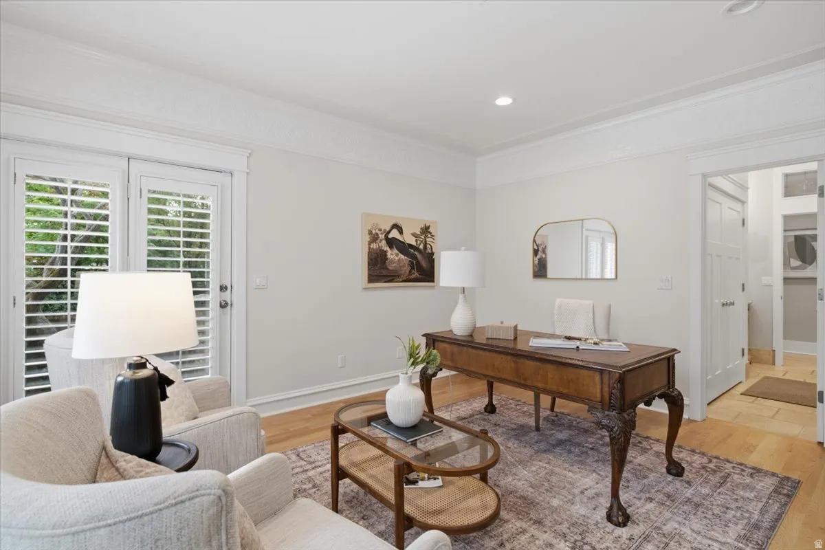 Wood-finish flooring, white plantation shutters, decorative crown molding, recessed lighting, and a doorway with white trim