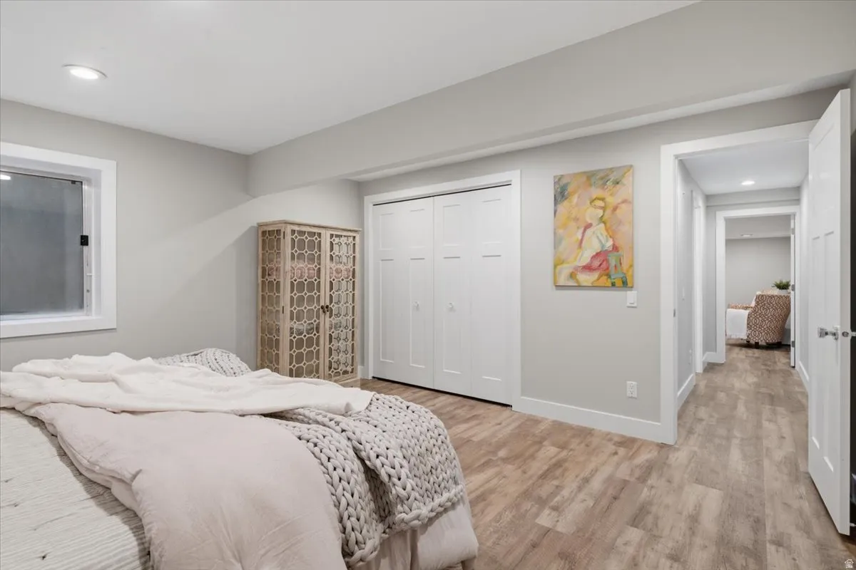 Recessed lighting, wood-finish flooring, white trim, and a built-in closet with bi-fold doors