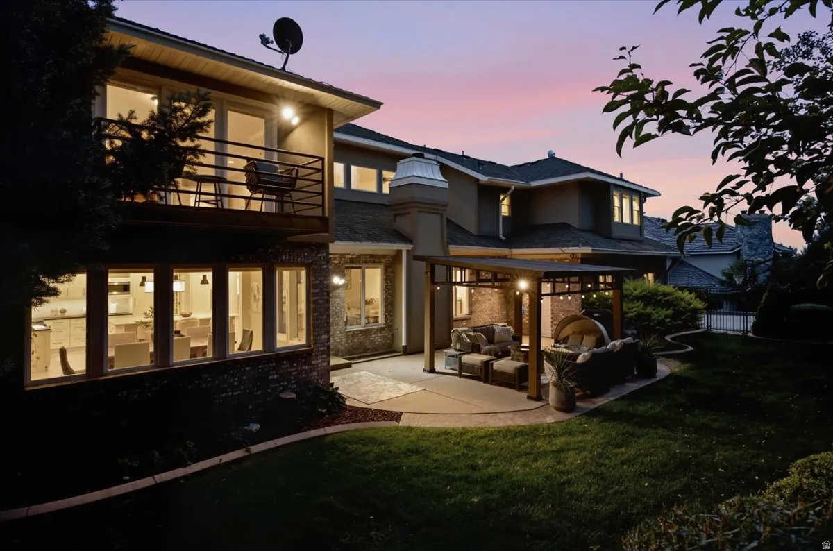 Extensive backyard with a manicured lawn, a large patio with a pergola, and a second-story balcony