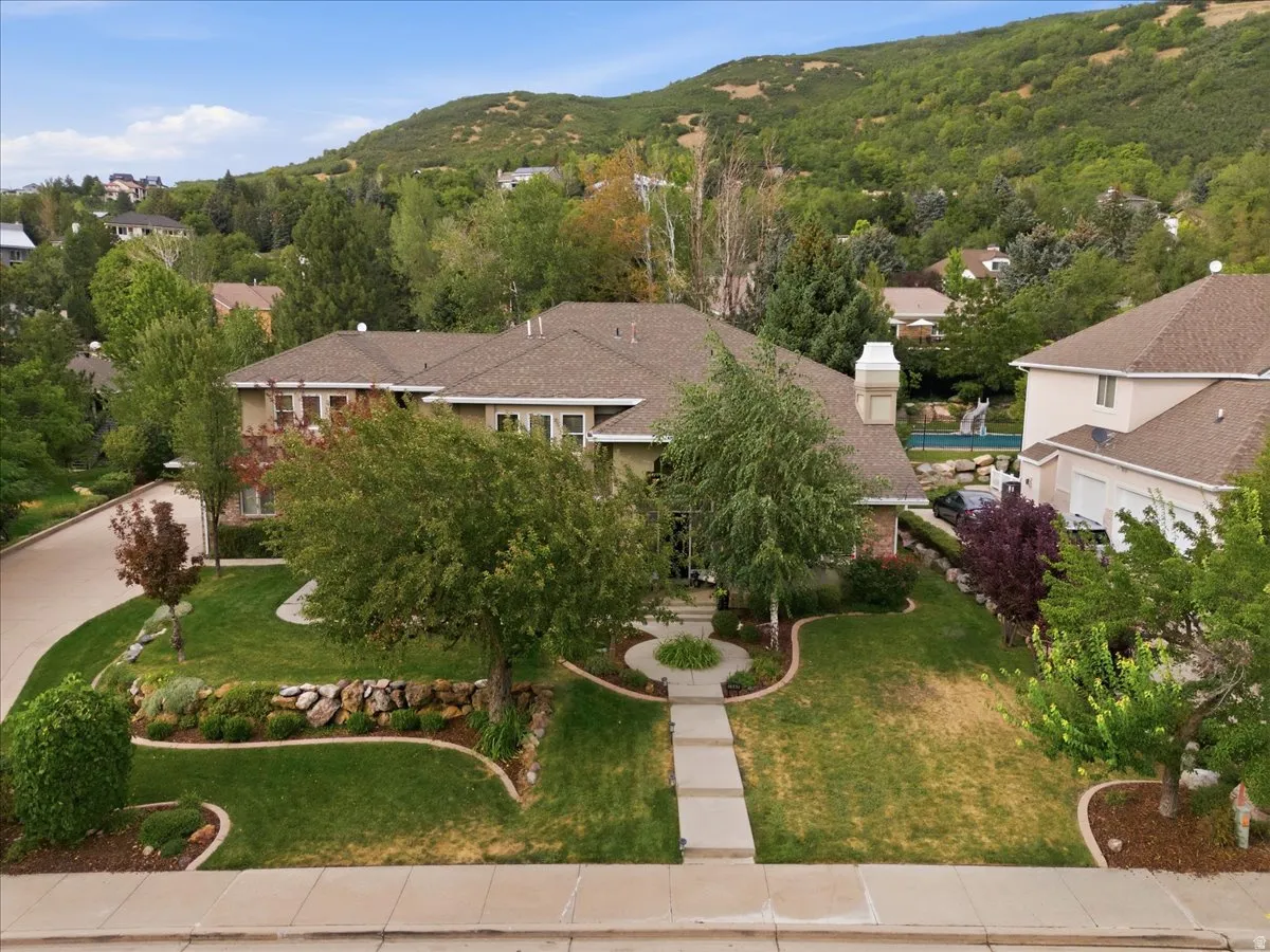 Traditional-style residence with a prominent chimney, a multi-car garage, and a landscaped front yard featuring a concrete walkway