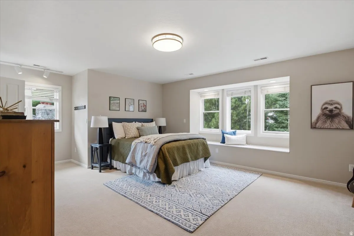 Wall-to-wall carpeted flooring, built-in window seating, three large windows, and track lighting