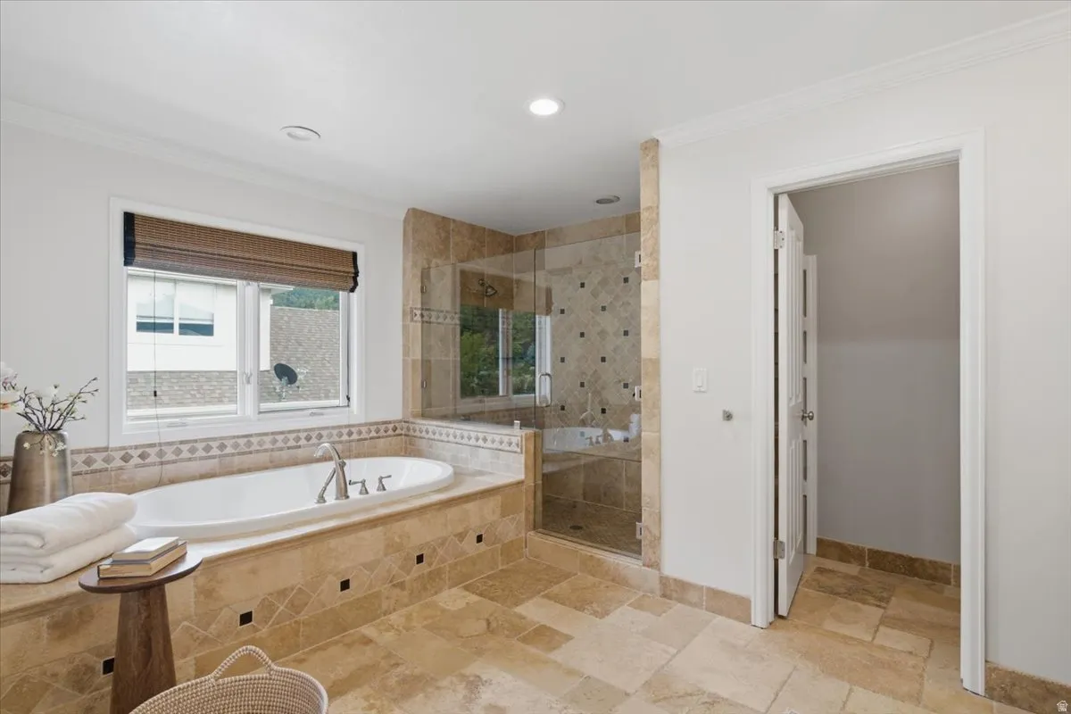 Spa-inspired bathroom featuring a built-in soaking tub with stone surround, a separate glass-enclosed shower, and stone tile flooring