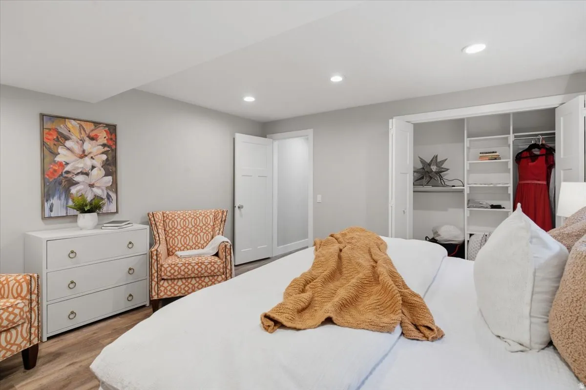 Recessed lighting illuminates the space, featuring wood-finish flooring and a white built-in closet system