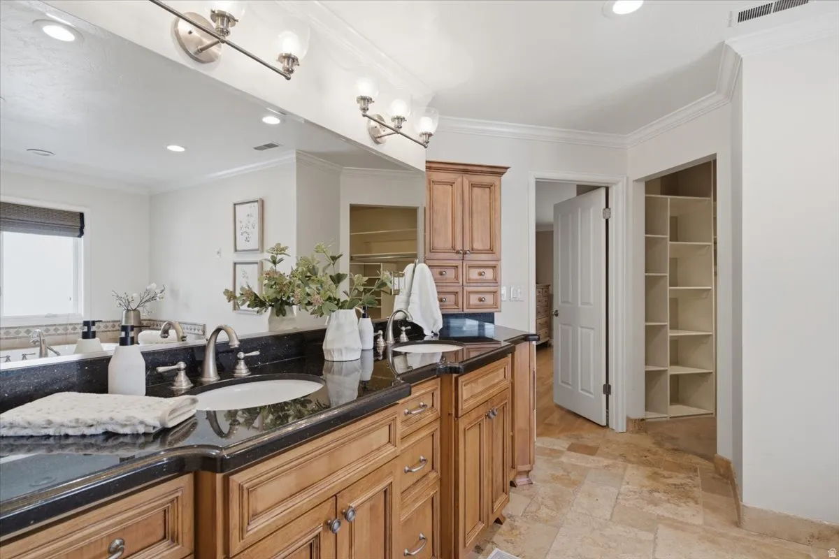 Dual vanity with undermount sinks, black countertop, and wood cabinetry